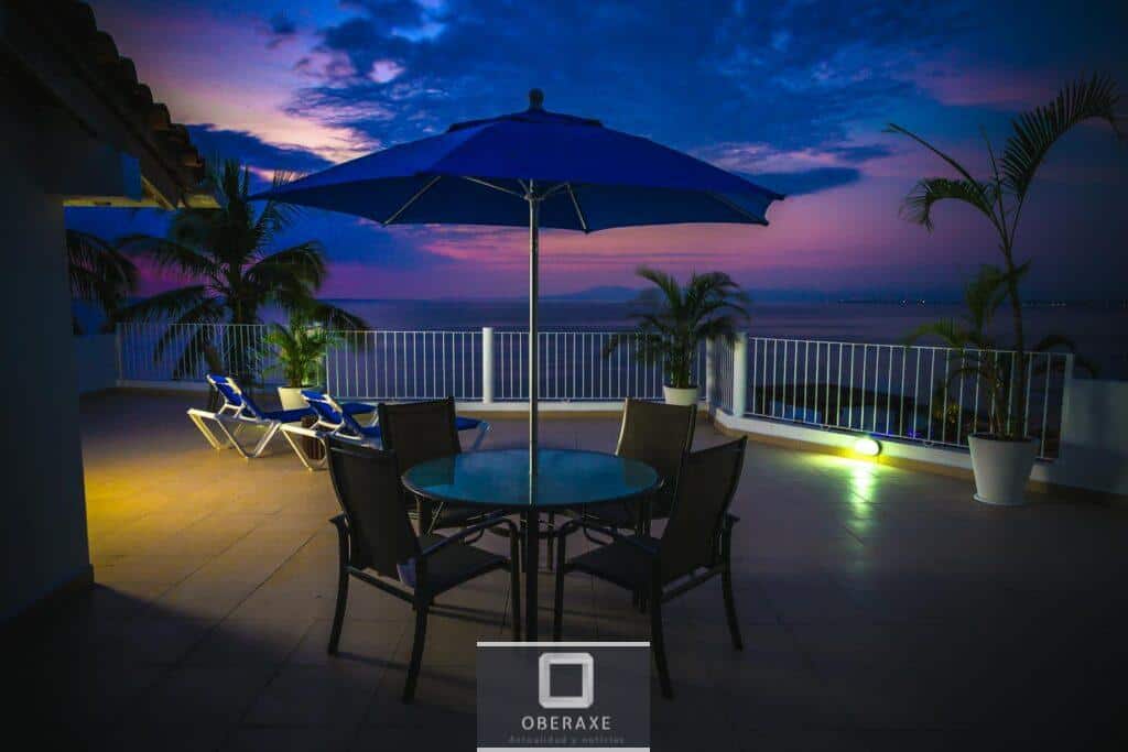 Stunning ocean view from a resort terrace at sunset with tropical plants and seating.